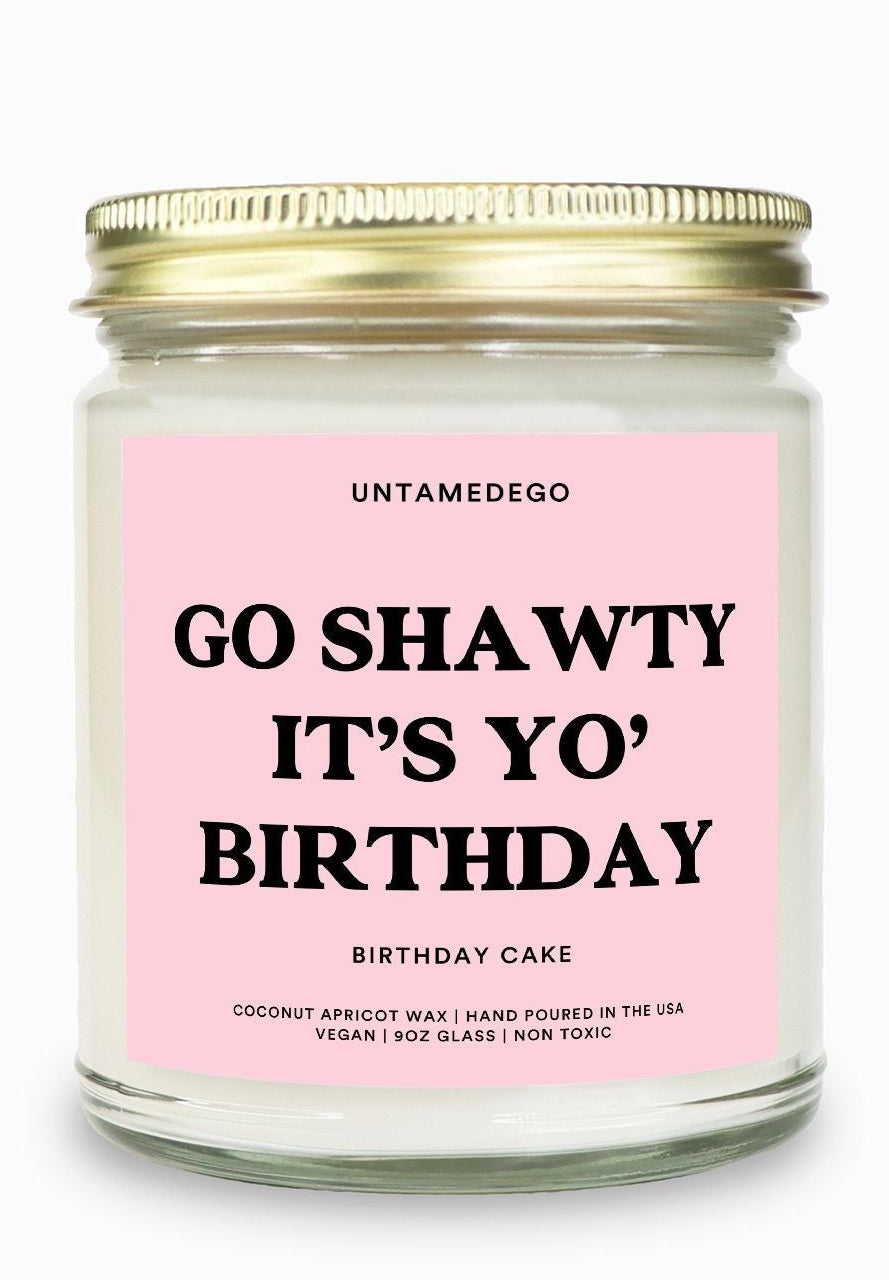 Candle with pink label and gold lid on a white background