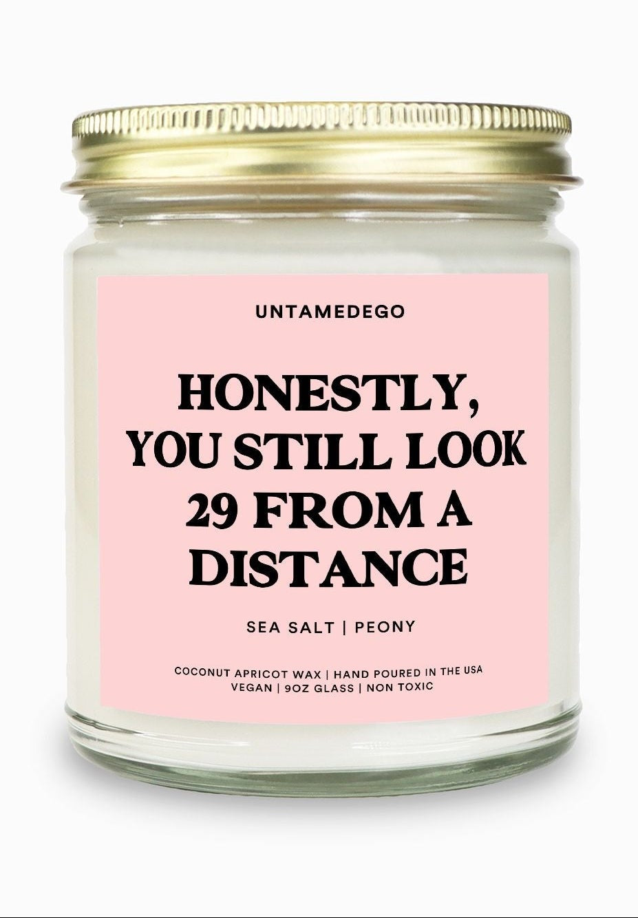 Candle with pink label and gold lid on a white background