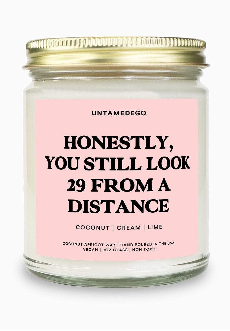 Candle with pink label and gold lid on a white background