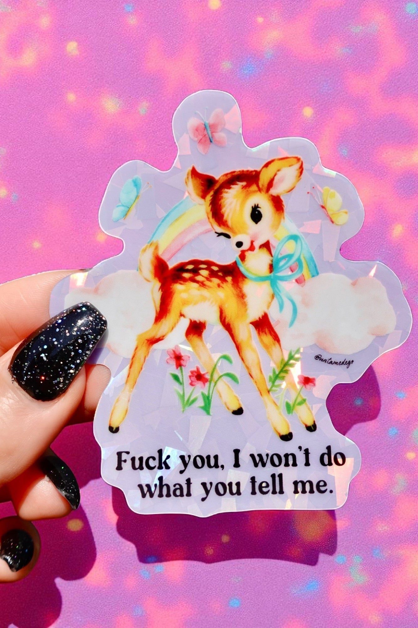 Sticker with a deer illustration and text held against a colorful, blurred background