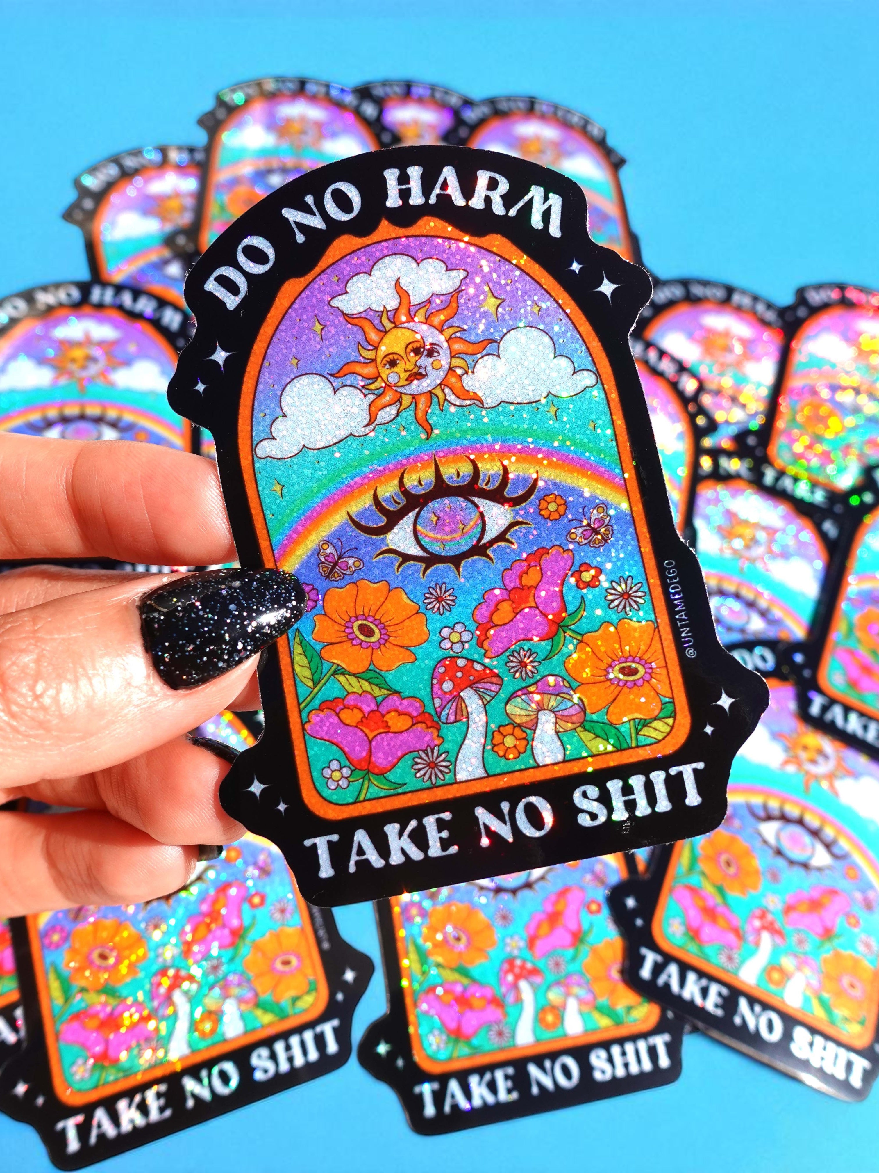 Colorful stickers with 'Do No Harm, Take No Shit' text held by a hand against a blue background.