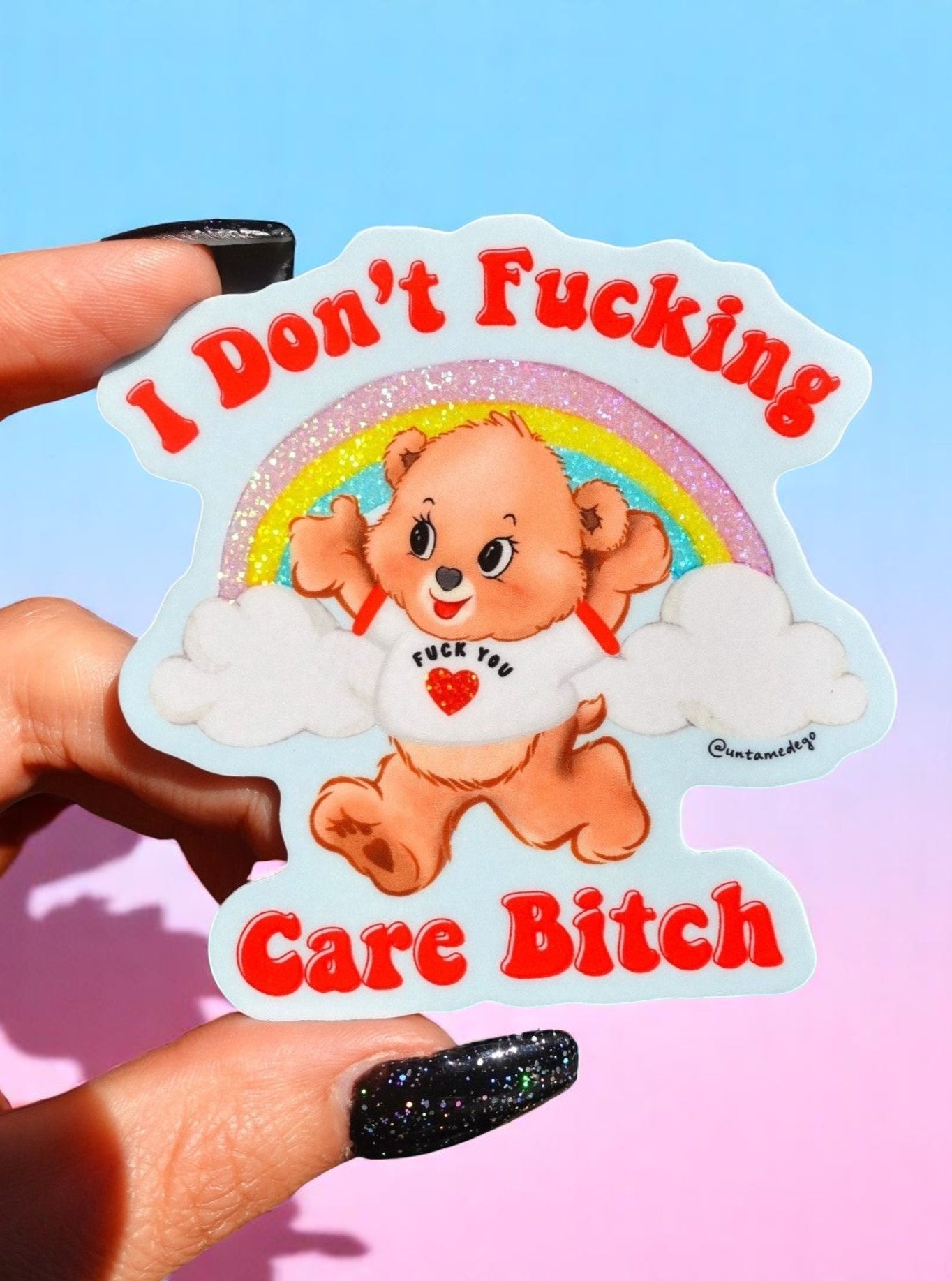 Sticker with a bear character and text held by a hand against a colorful background