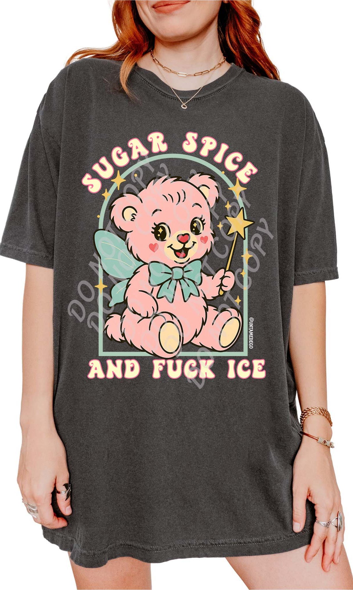 Person wearing a pepper graphic t-shirt featuring a pastel illustrated bear holding a wand and text that reads Sugar Spice and Fuck ICE, photographed against a white background