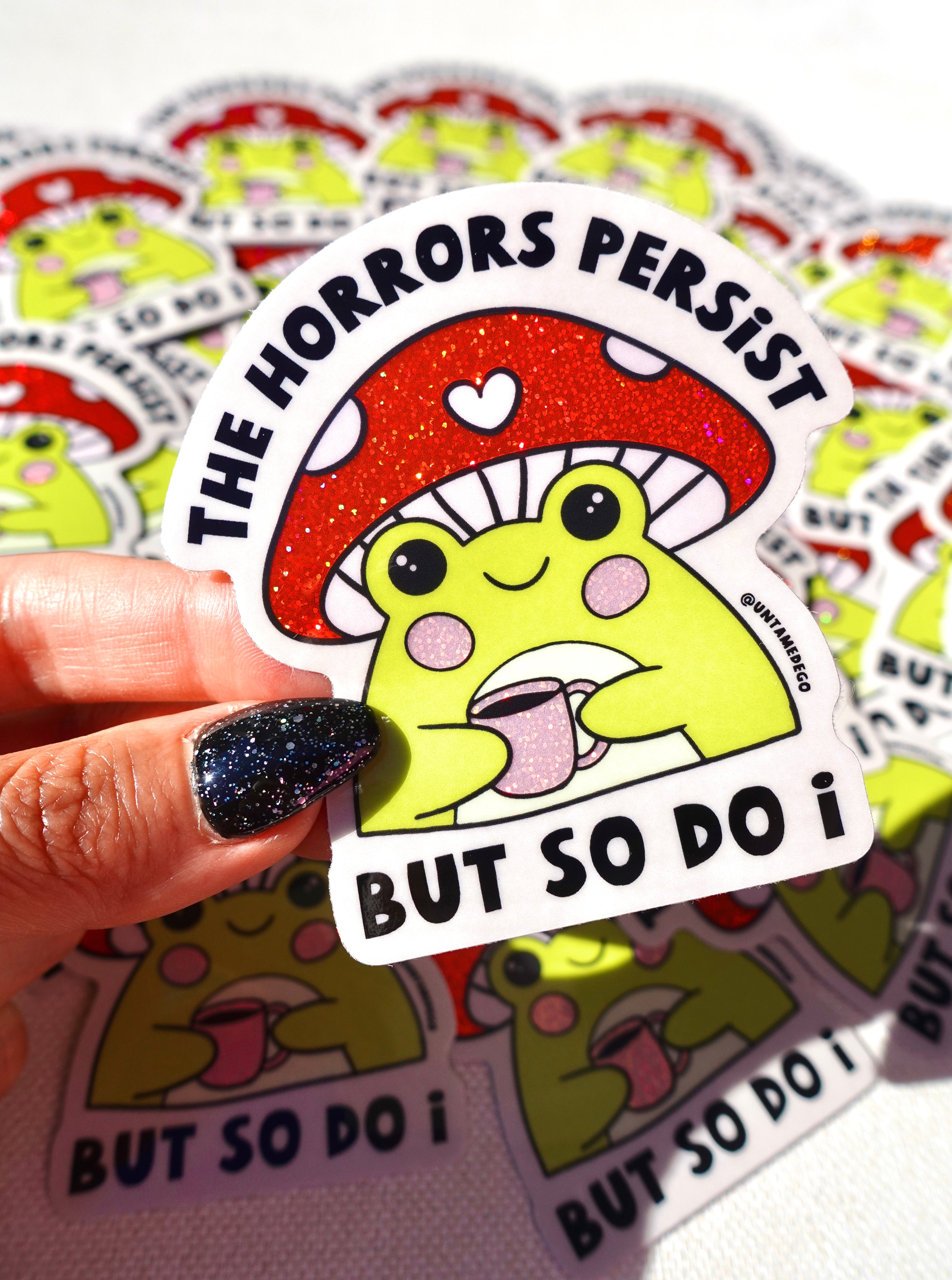 Sticker with a mushroom and text held by a hand, surrounded by more stickers.