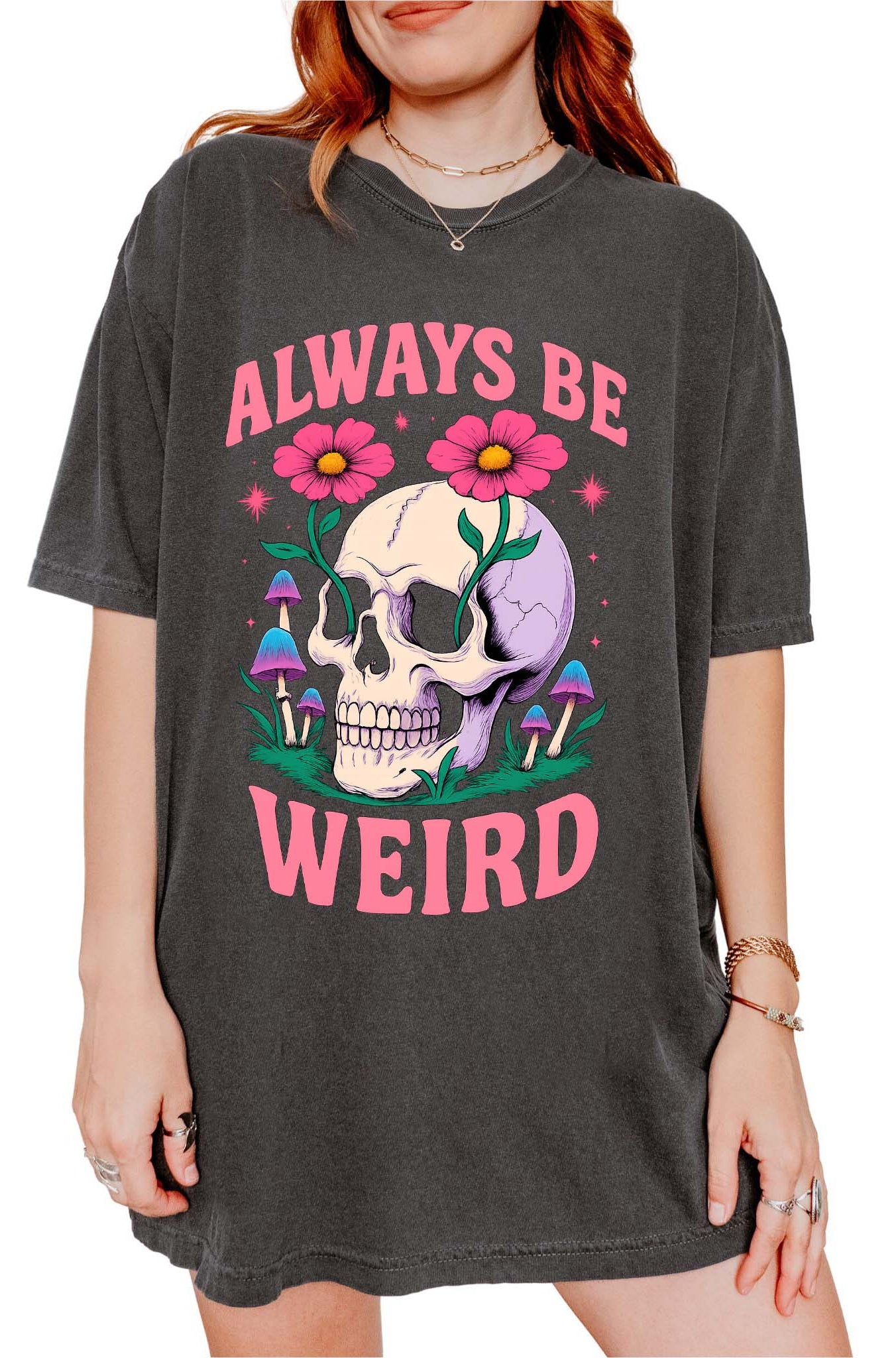 Graphic t-shirt with skull, flowers, and mushrooms design and text saying always be weird