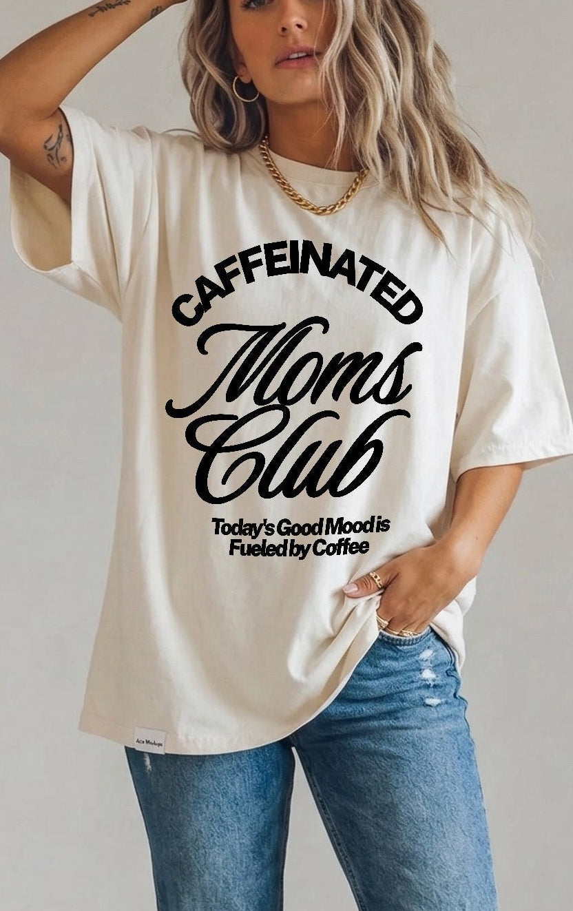 Woman wearing a 'Caffeinated Moms Club' t-shirt and ripped jeans against a plain background