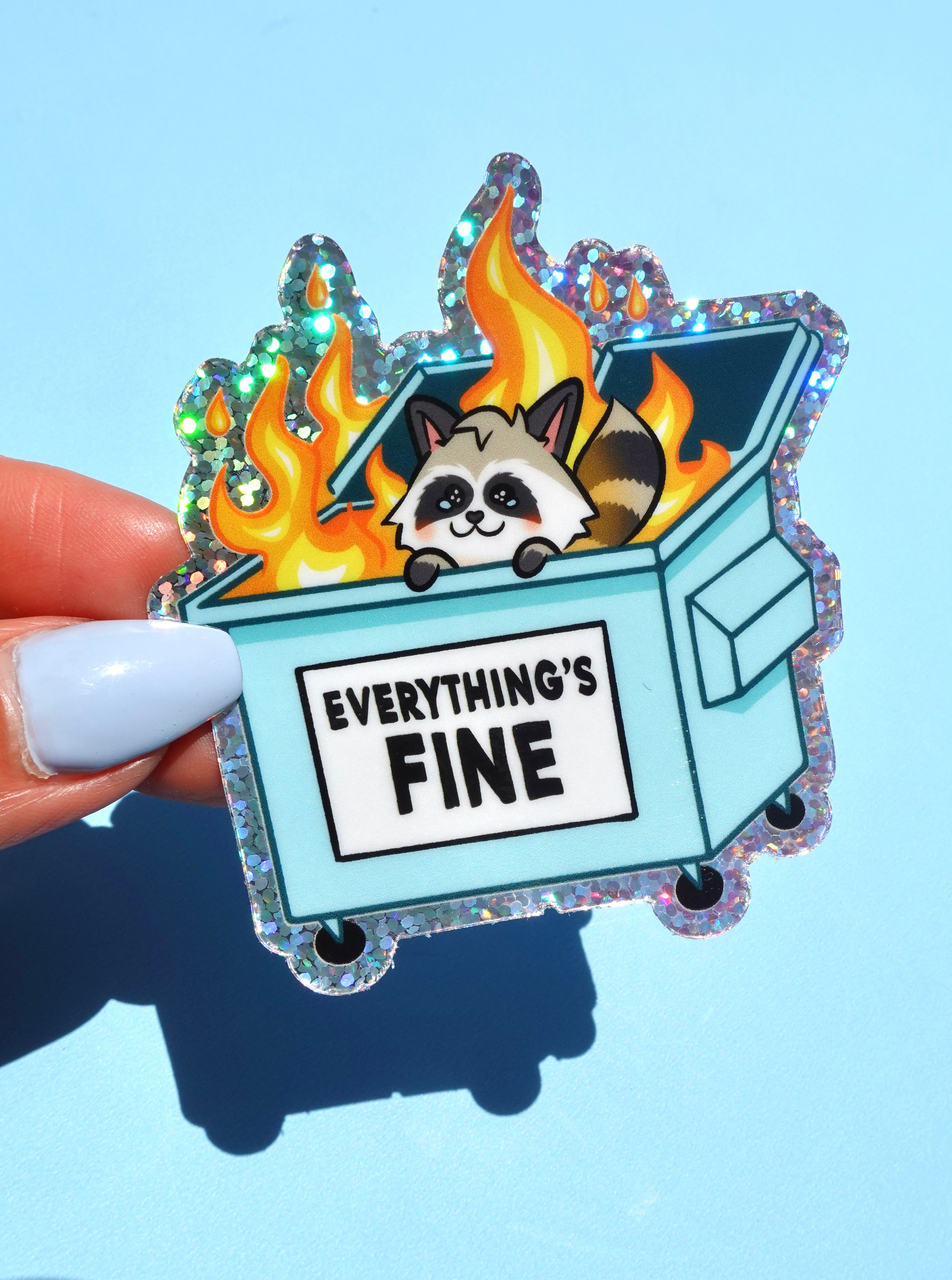 Funny holographic vinyl sticker with raccoon in a flaming dumpster. Text reads “Everything’s Fine.” Waterproof, glossy finish, and emotionally relatable.