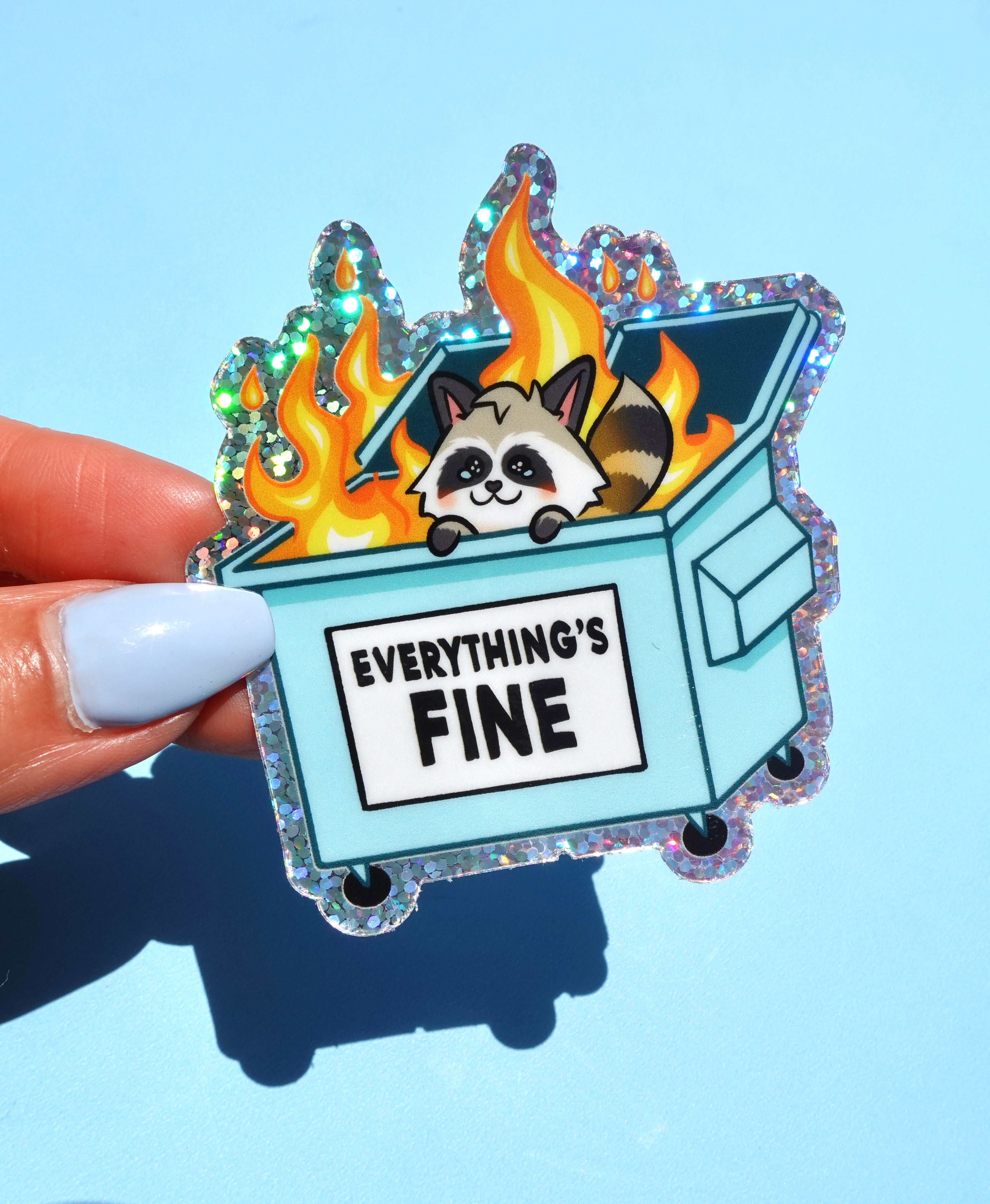 Funny holographic vinyl sticker with raccoon in a flaming dumpster. Text reads “Everything’s Fine.” Waterproof, glossy finish, and emotionally relatable.