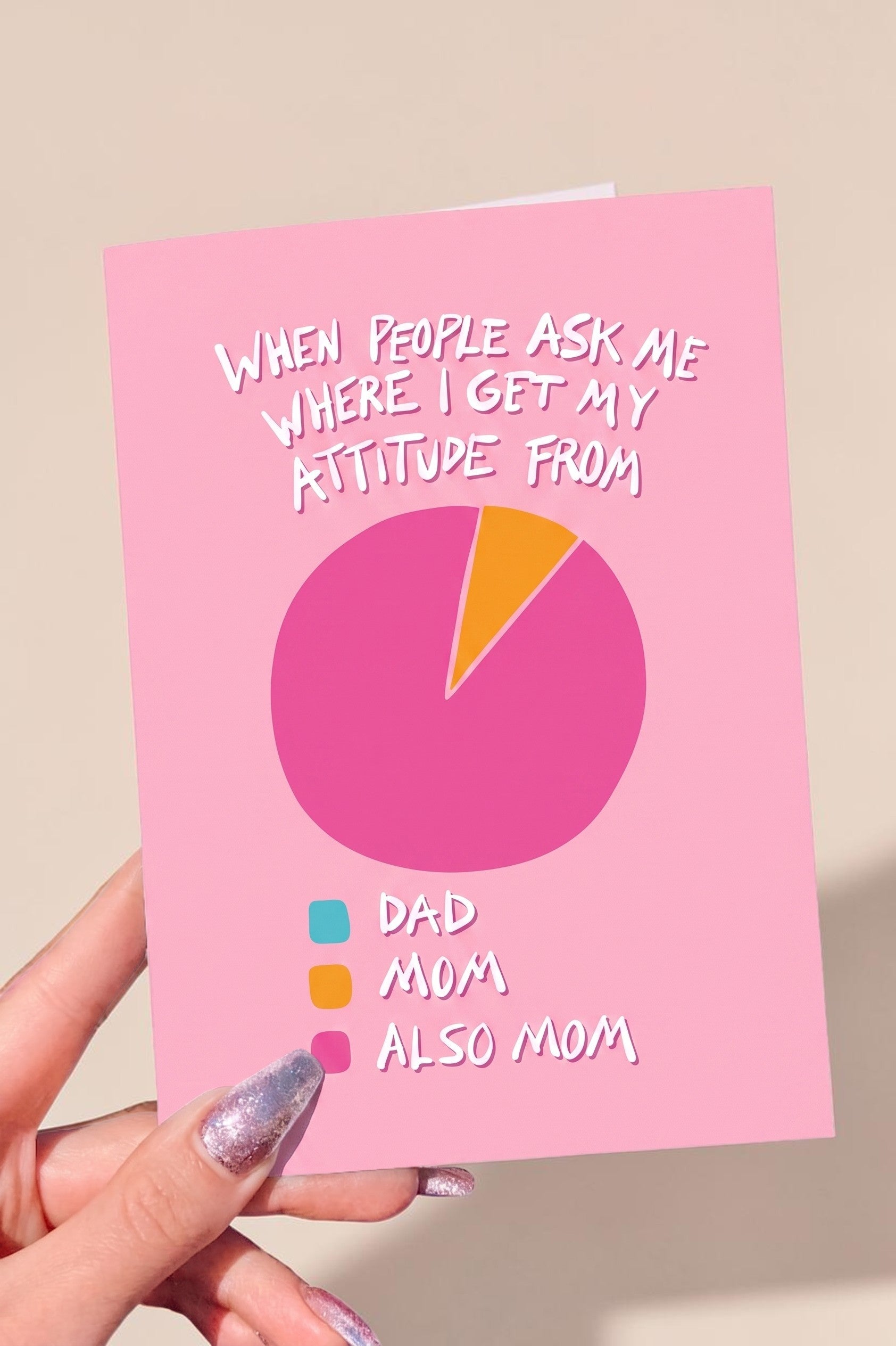 Pink card with pie chart and text about attitude inheritance, held by a hand.