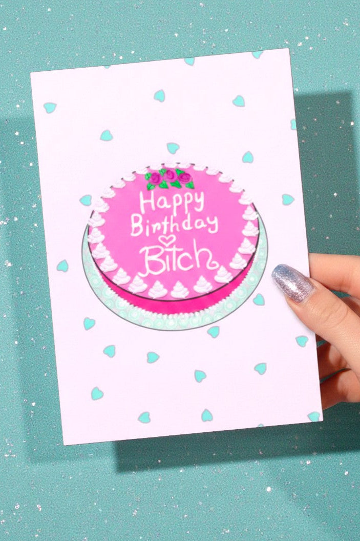 Birthday greeting card featuring a pink illustrated cake with the words Happy Birthday on the cake and small heart graphics on a pastel background, photographed against a teal glitter background