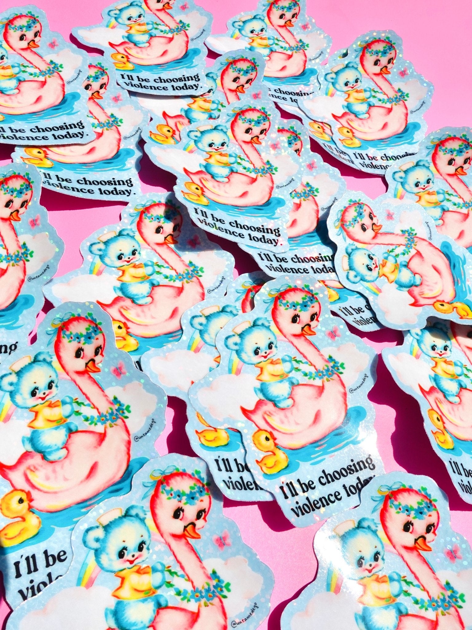 Holographic die-cut sticker reading "I'll be choosing violence today" held by a hand with light blue nails against a pink background, shown alongside multiple stickers scattered on a pink surface.