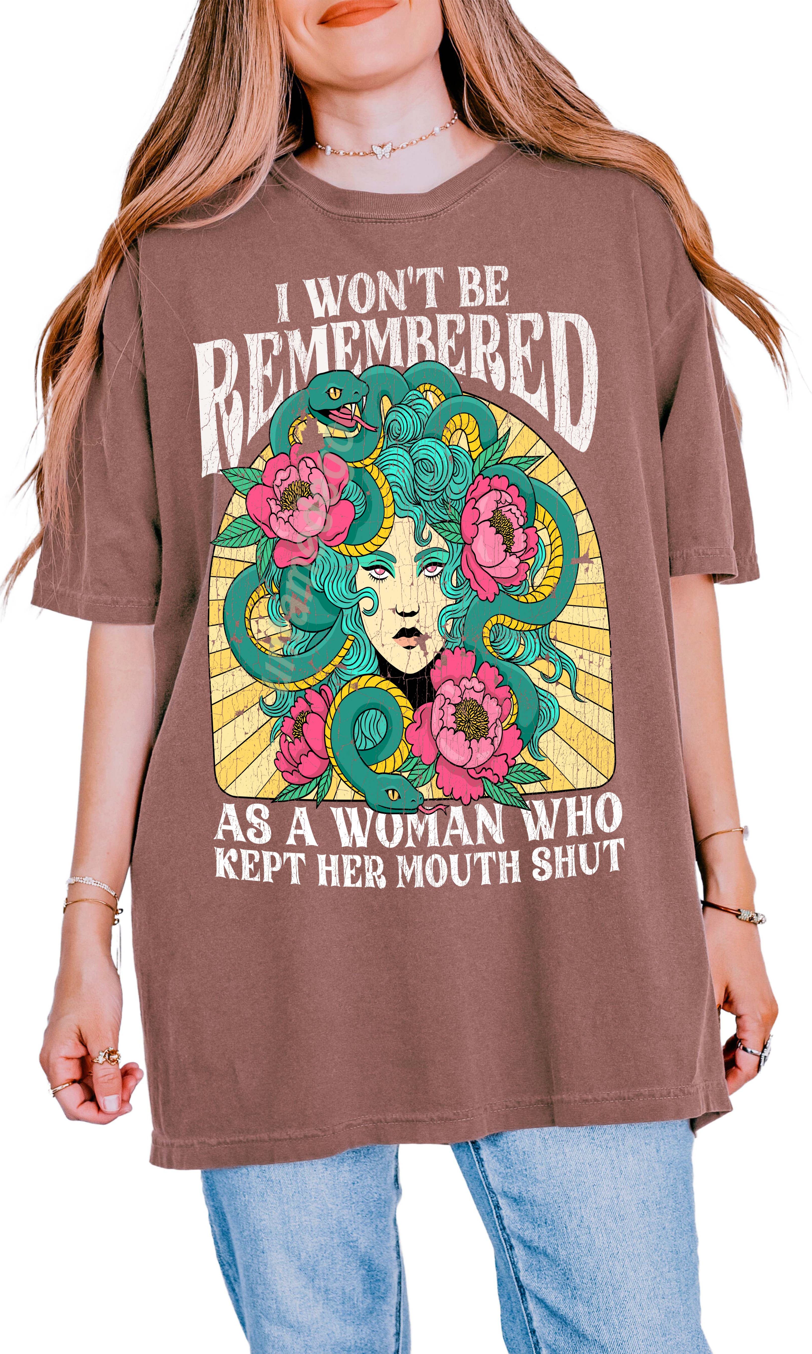 A woman modeling a white crew neck t-shirt with a graphic print in the center that reads 'I Won't Be Remembered As A Woman Who Kept Her Mouth Shut' surrounded by floral designs.