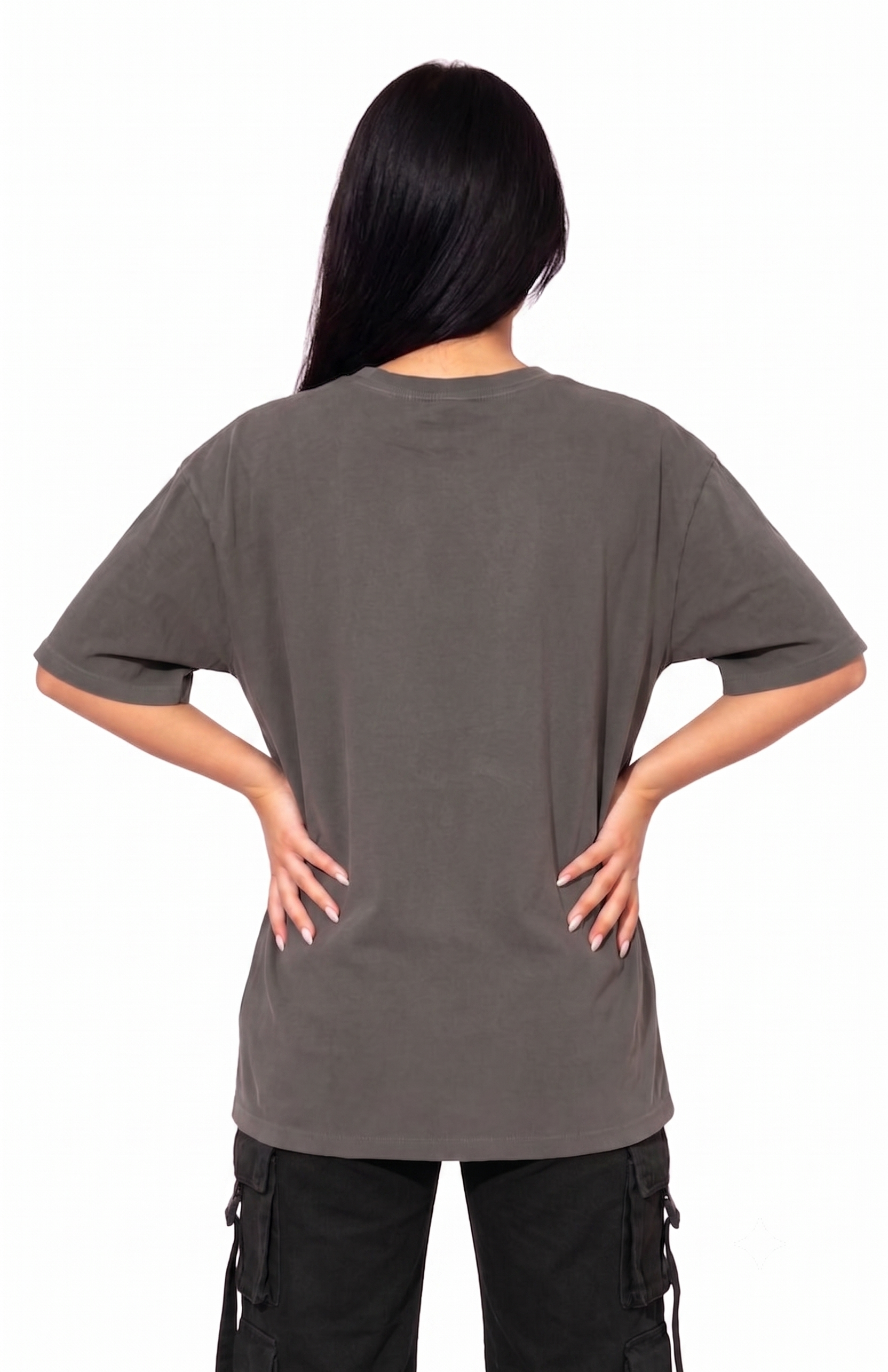 A woman viewed from the back wearing an oversized short-sleeve t-shirt in a washed dark gray color, paired with black cargo pants, against a plain white background.