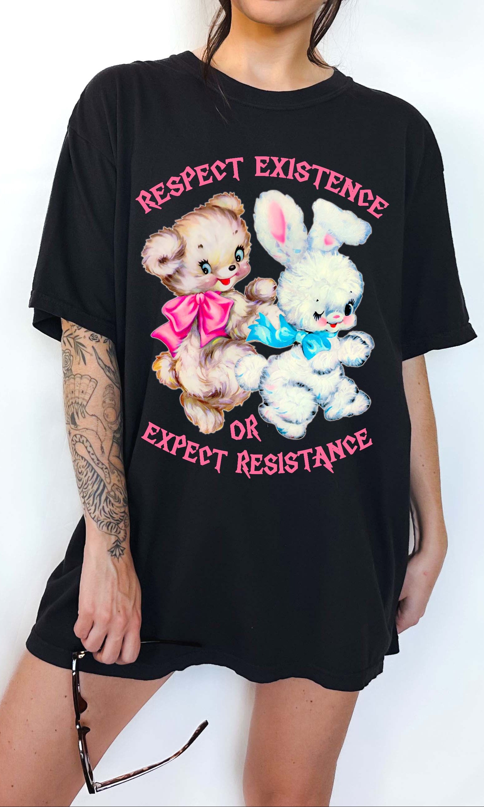 Person wearing a black graphic t-shirt featuring two illustrated characters and the text Respect Existence Or Expect Resistance, photographed against a light background
