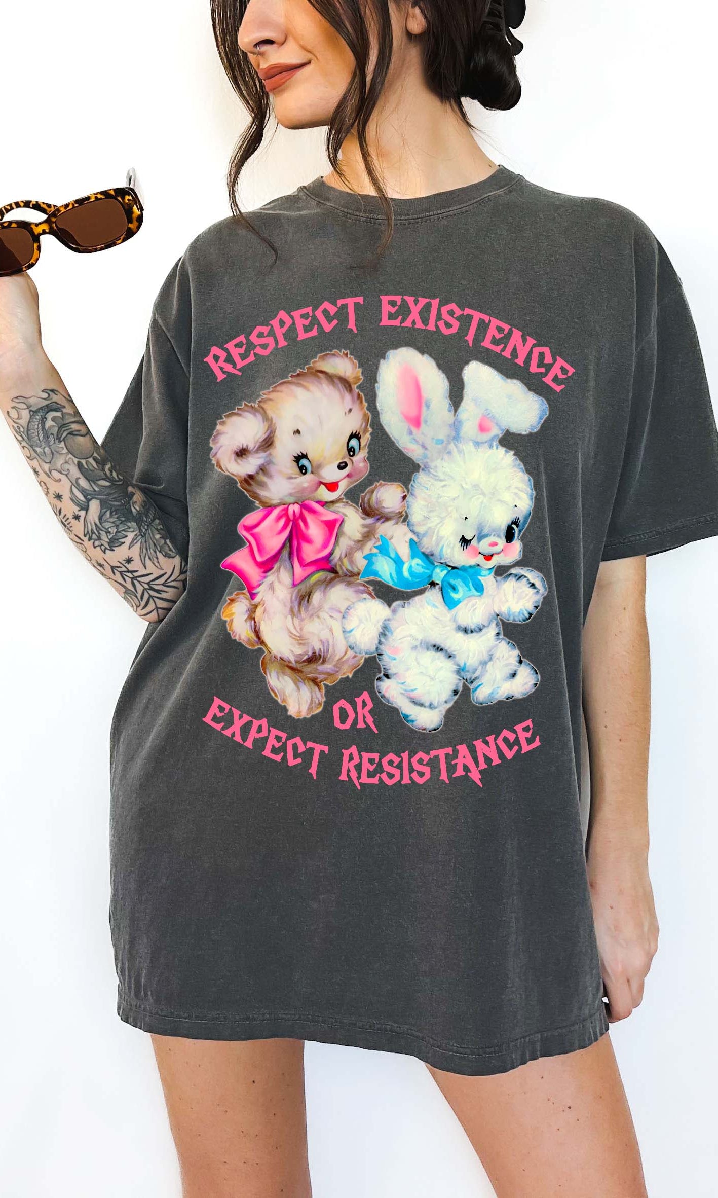 Person wearing a dark gray graphic t-shirt featuring two illustrated characters and the text Respect Existence Or Expect Resistance, photographed against a light background