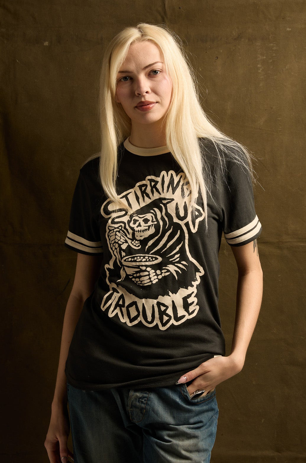 Person wearing a black t-shirt with graphic design against a brown backdrop