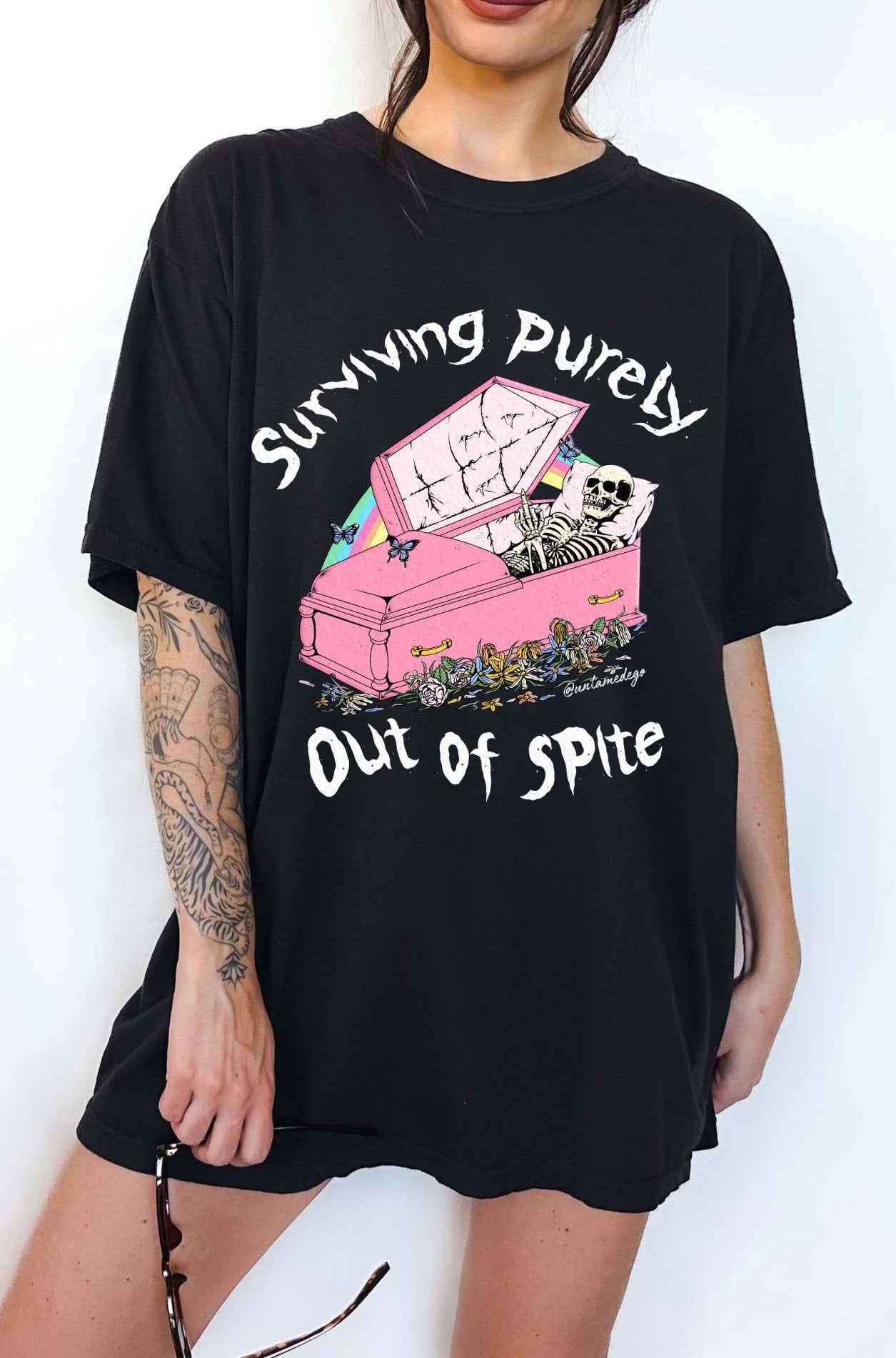 Funny graphic t-shirt with skeleton in coffin and text saying surviving purely out of spite