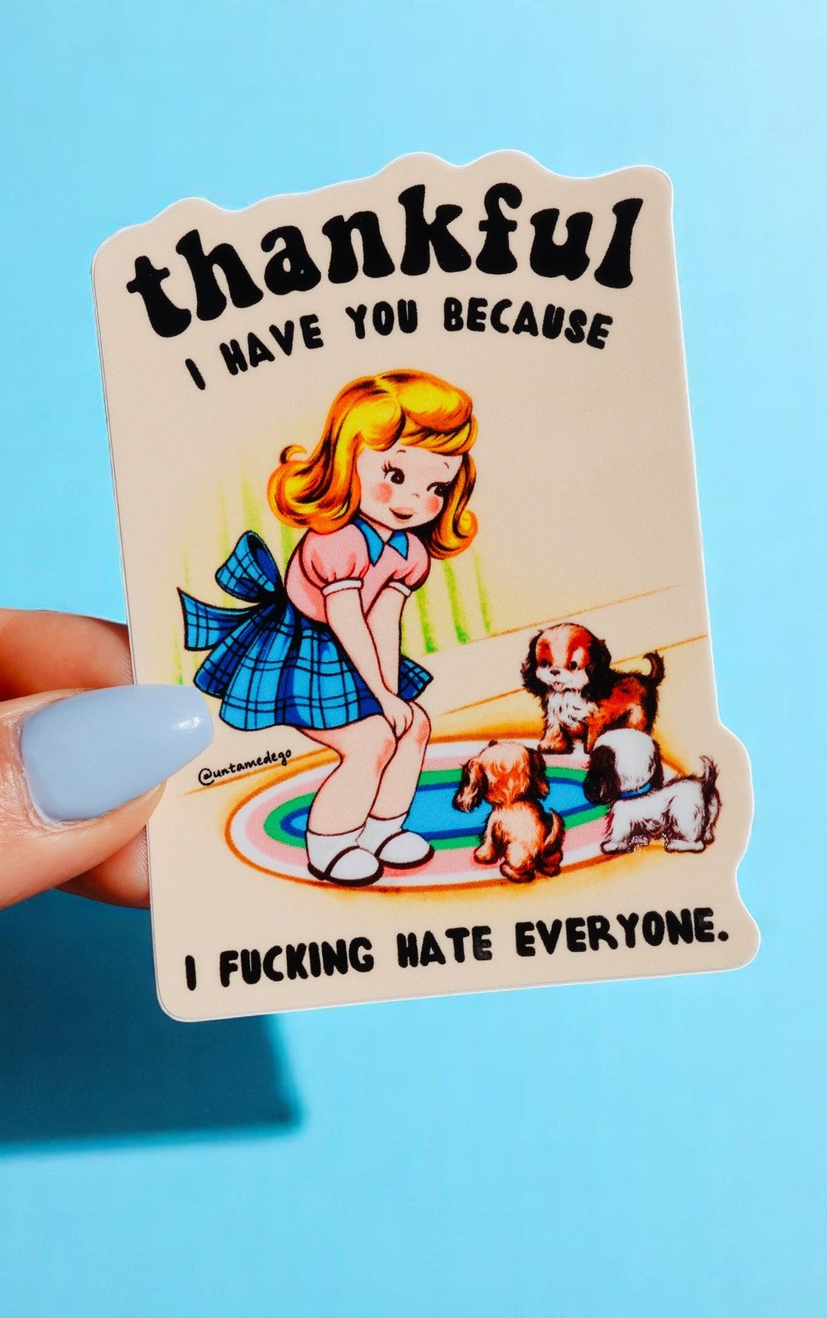 Die-cut glossy vinyl sticker featuring a retro-style illustration of a blonde girl in a blue dress sitting on a rug with two puppies. Text reads: Thankful I Have You Because I Fucking Hate Everyone.