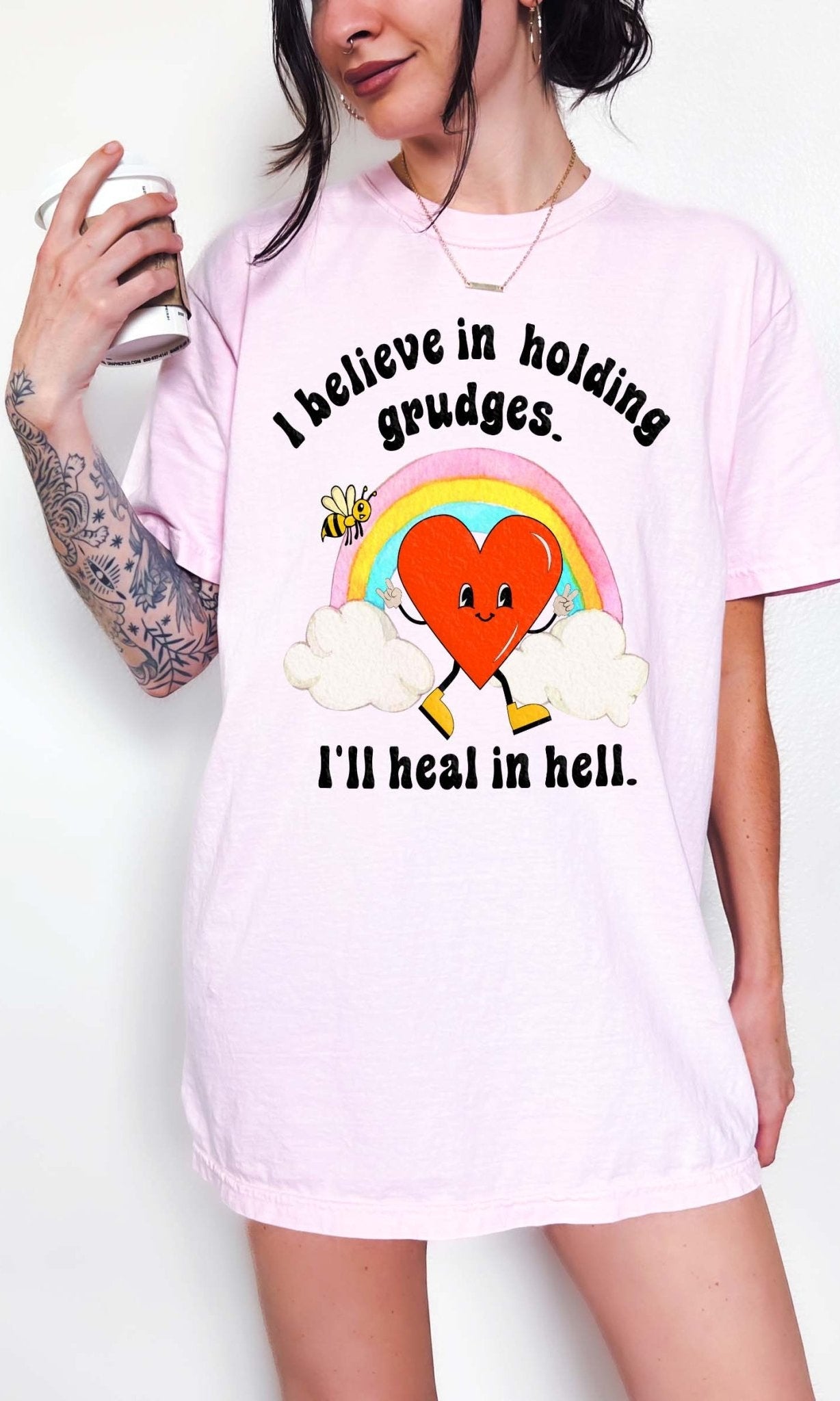 Funny sarcastic black t-shirt with retro heart and rainbow graphic reading I believe in holding grudges I’ll heal in hell