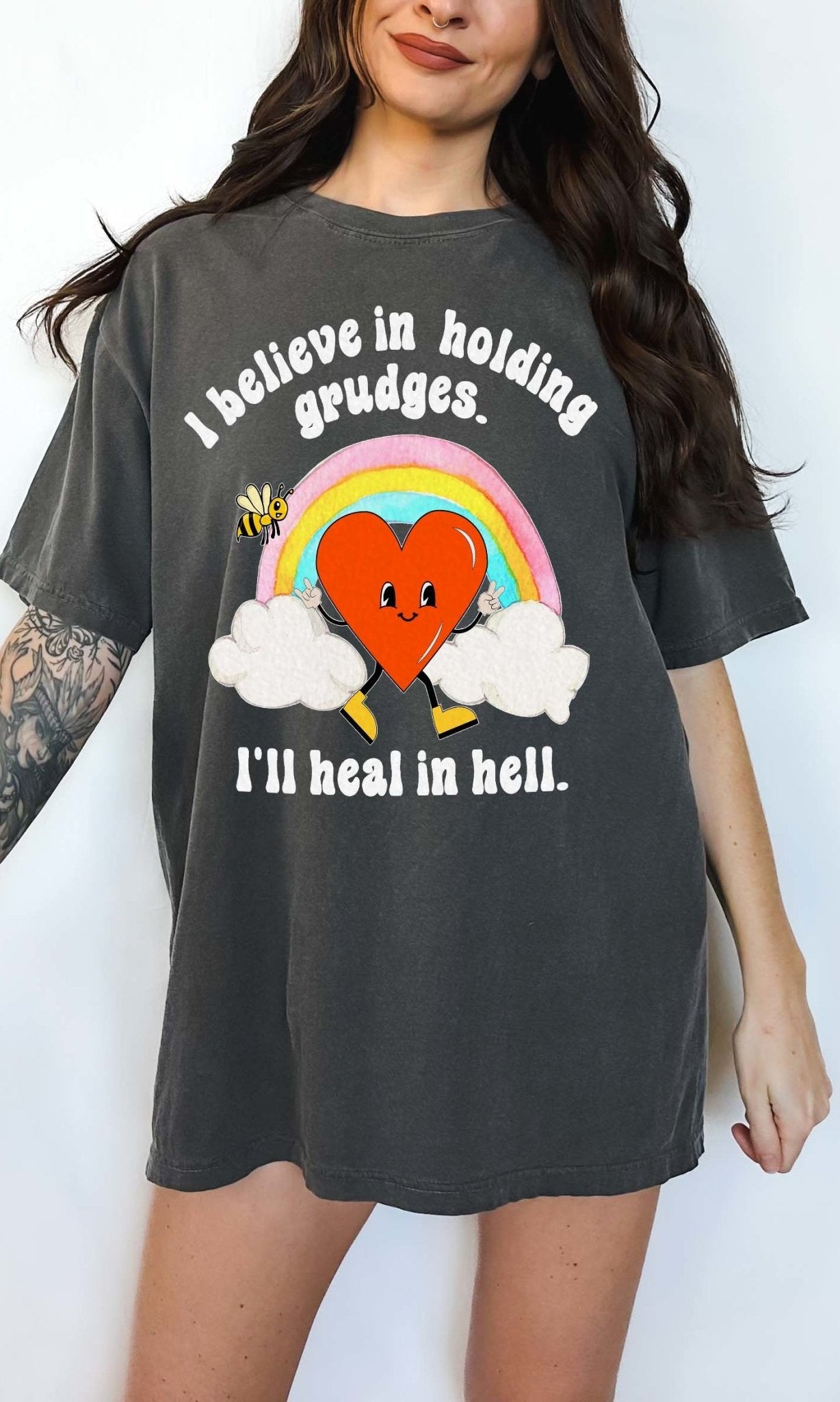 Funny sarcastic black t-shirt with retro heart and rainbow graphic reading I believe in holding grudges I’ll heal in hell