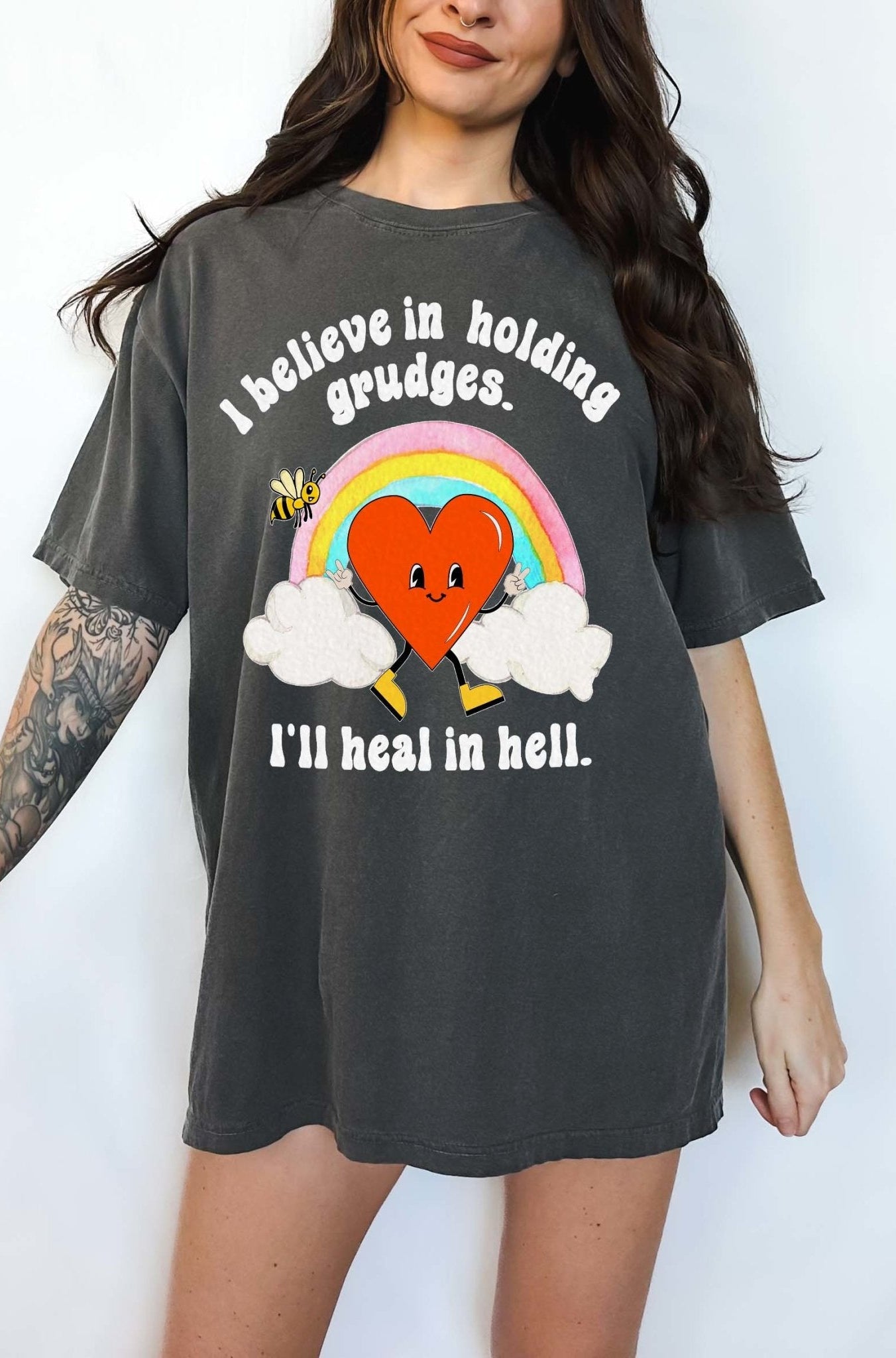 Funny sarcastic black t-shirt with retro heart and rainbow graphic reading I believe in holding grudges I’ll heal in hell