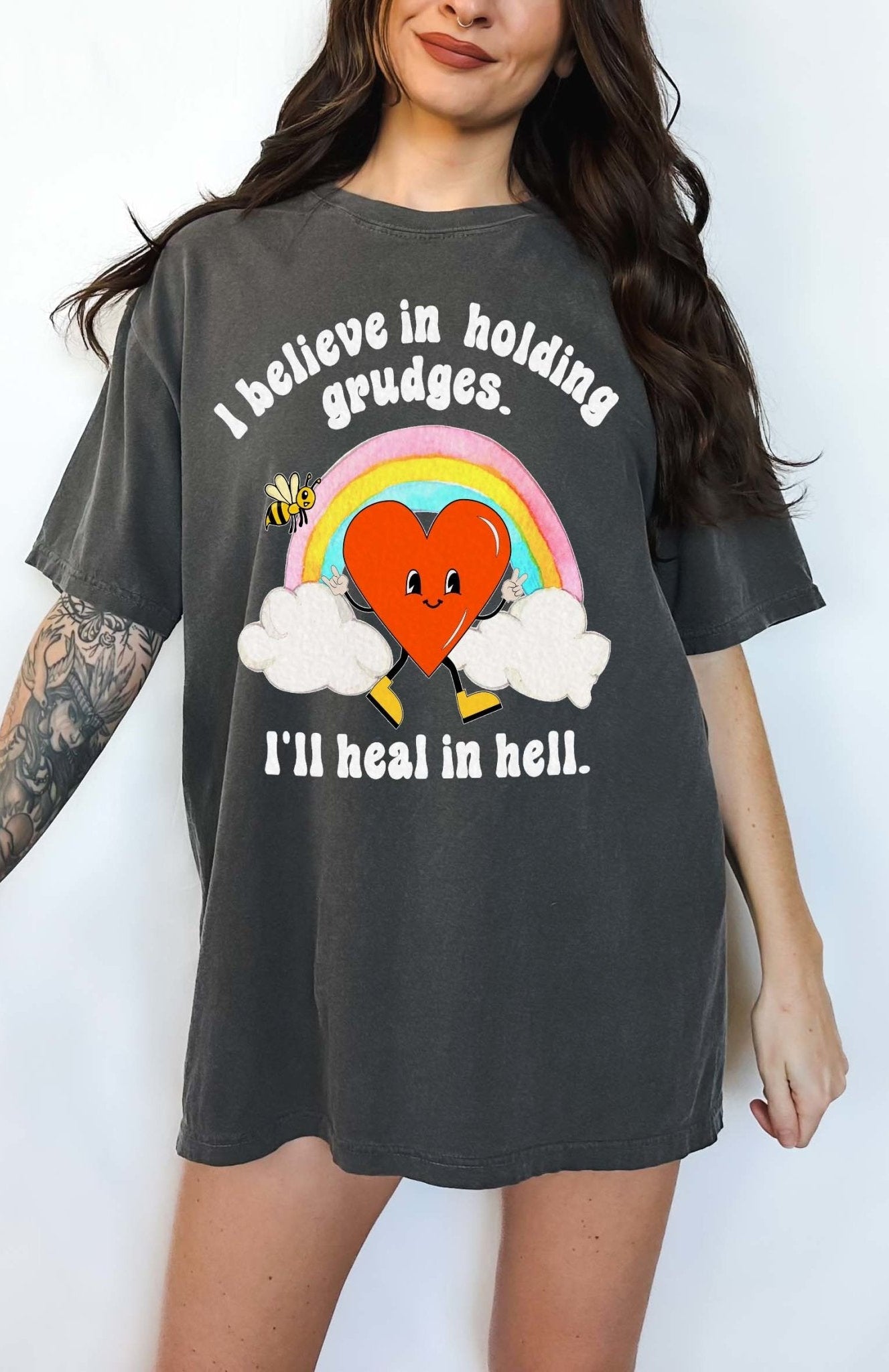 Funny sarcastic black t-shirt with retro heart and rainbow graphic reading I believe in holding grudges I’ll heal in hell