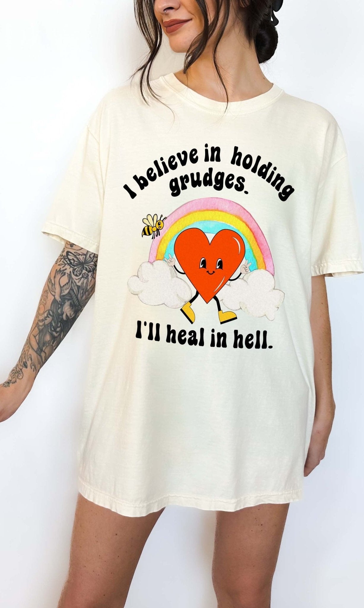 Funny sarcastic black t-shirt with retro heart and rainbow graphic reading I believe in holding grudges I’ll heal in hell