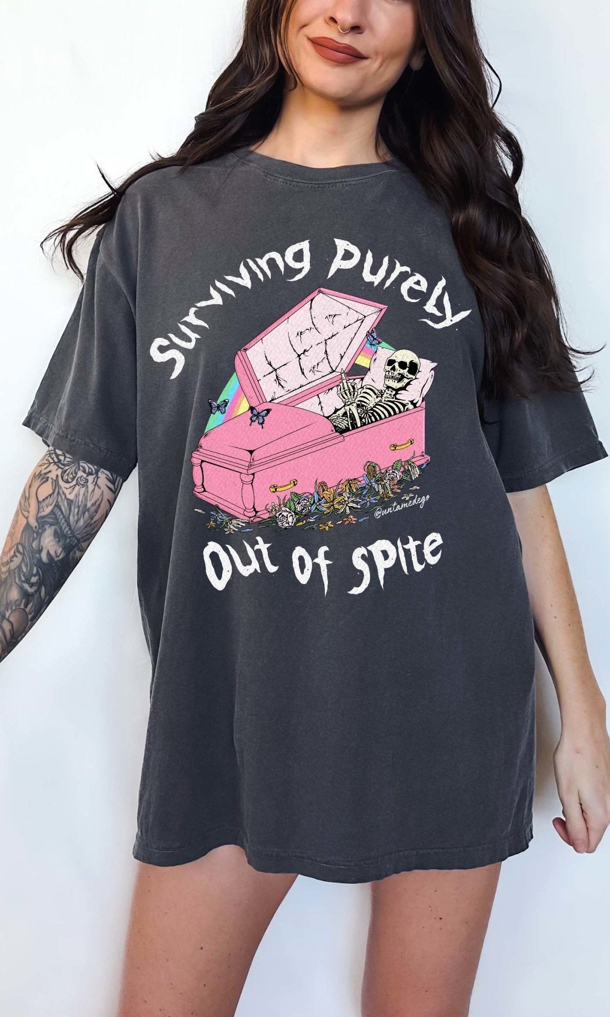 Funny graphic t-shirt with skeleton in coffin and text saying surviving purely out of spite