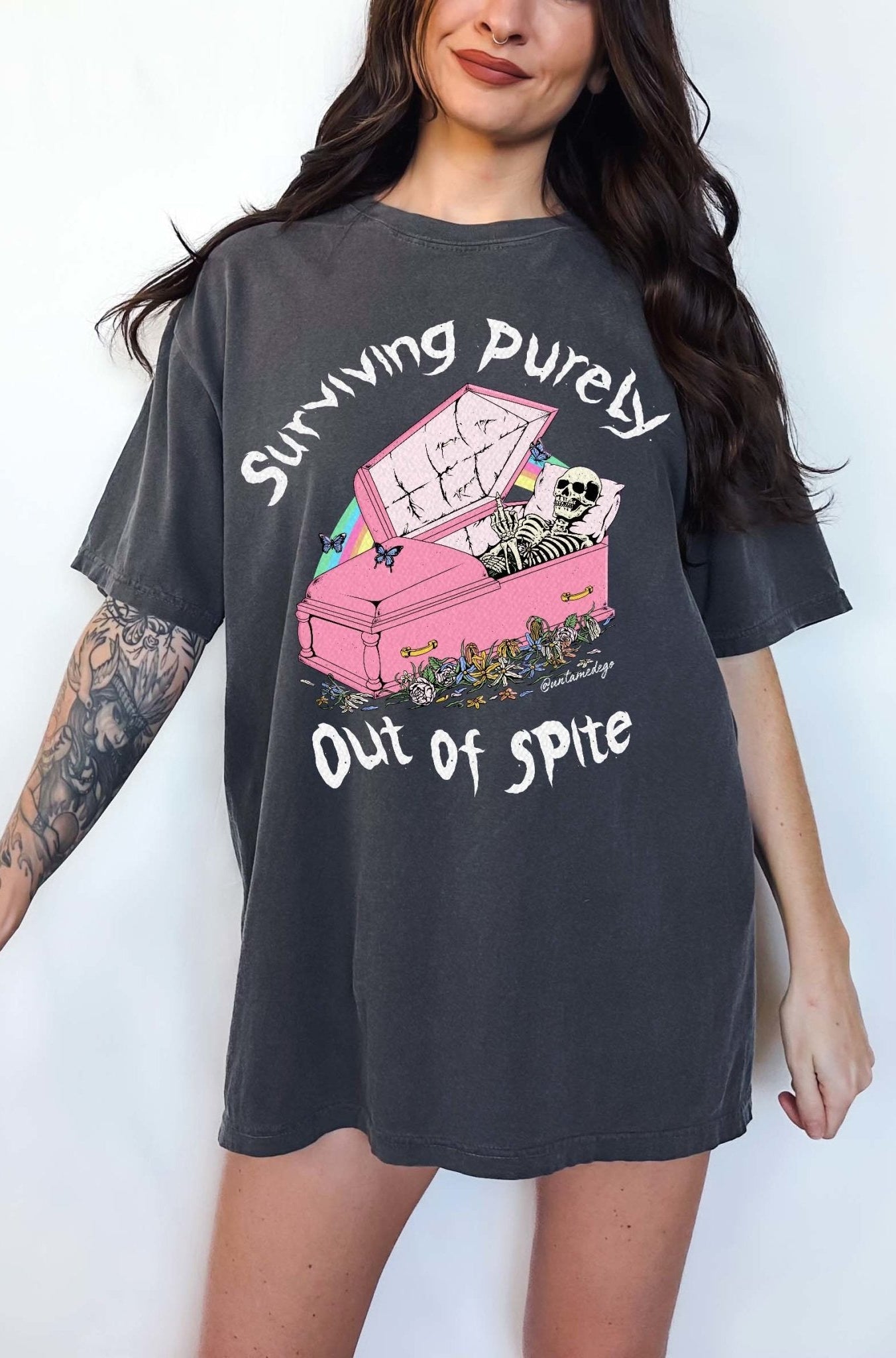 Funny graphic t-shirt with skeleton in coffin and text saying surviving purely out of spite