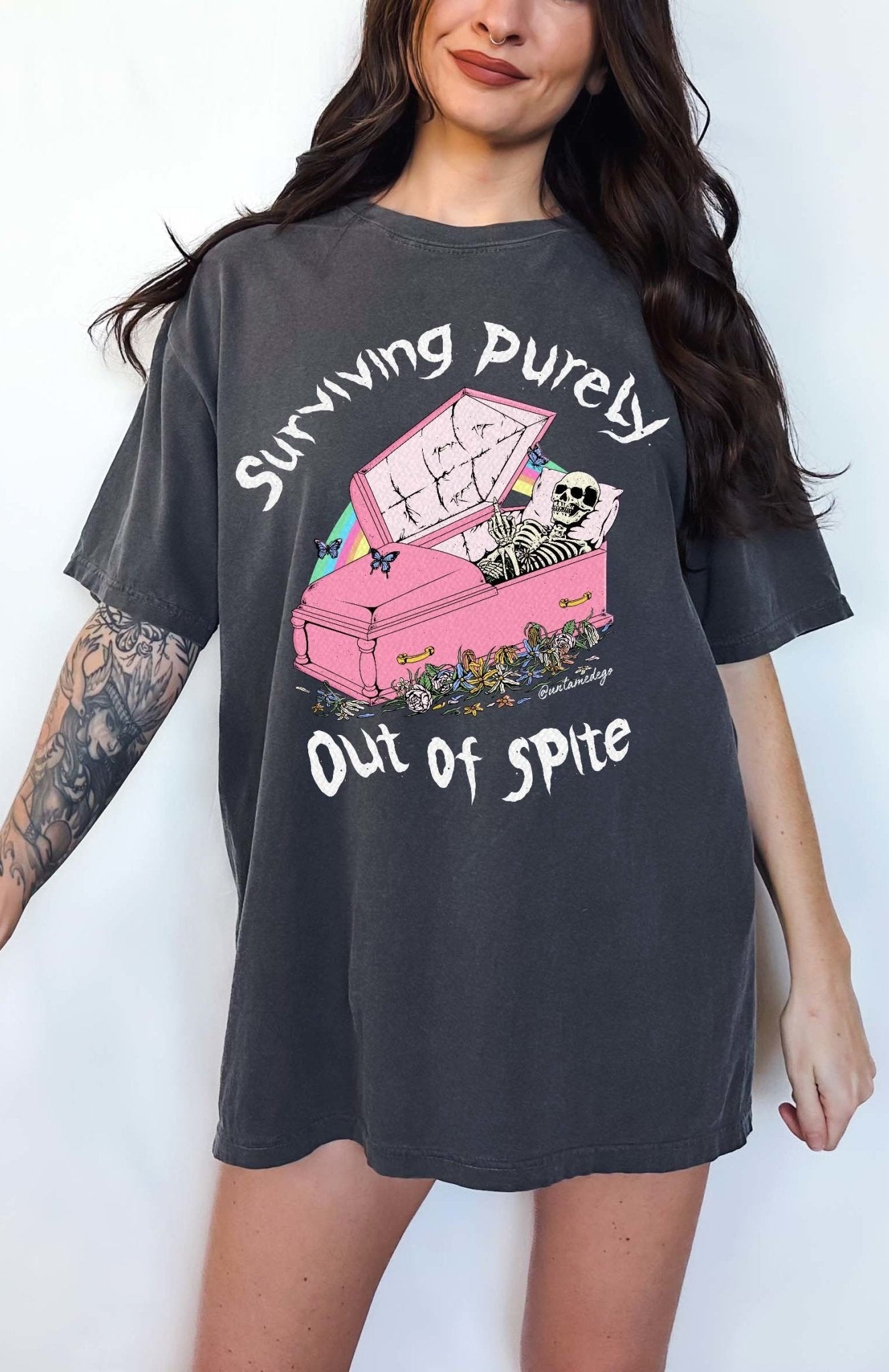 Funny graphic t-shirt with skeleton in coffin and text saying surviving purely out of spite