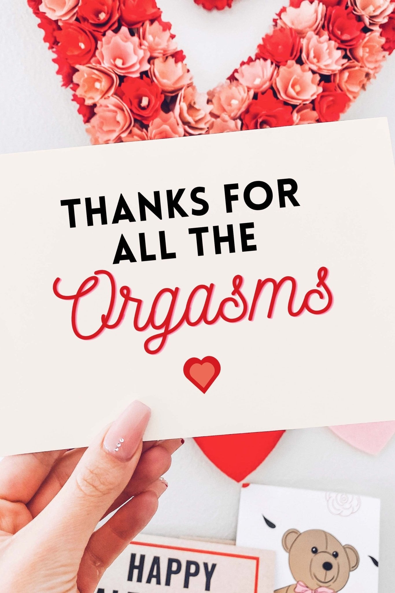 Greeting card with black and red text and a heart graphic on white festive background, photographed being held by a hand