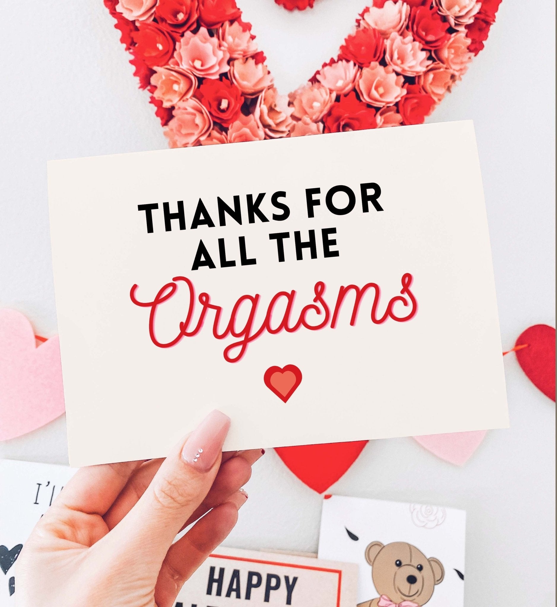 Greeting card with black and red text and a heart graphic on white festive background, photographed being held by a hand
