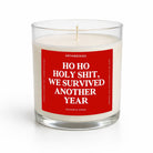 A clear glass jar candle with white wax and a bold red front label reading 'HO HO HOLY SHIT, WE SURVIVED ANOTHER YEAR' in white text. The brand name UNTAMEDEO is visible at the top of the label, with 'BALSAM & CEDAR' at the bottom.