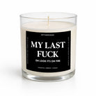 A white soy wax candle in a clear glass jar with a black square label that reads 'MY LAST FUCK OH LOOK IT'S ON FIRE' and smaller text 'UNTAMEDEGO' and 'COASTAL AMBER | CEDAR'.