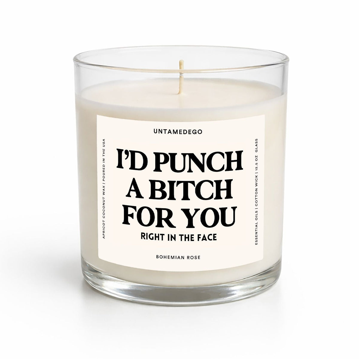 A clear glass jar candle with cream-colored wax and a white label featuring bold black text that reads, 'I'D PUNCH A BITCH FOR YOU RIGHT IN THE FACE' by Untamedigo, Bohemian Rose.