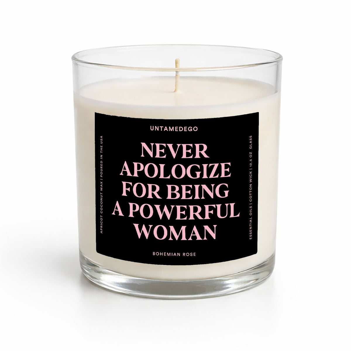 A clear glass jar candle with white wax and a black label featuring pink text that reads, 'NEVER APOLOGIZE FOR BEING A POWERFUL WOMAN' by Untamedogo.
