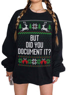 A person wearing a black oversized Christmas sweater with a festive green, red, and white knit pattern featuring reindeer, snowflakes, and the text 'BUT DID YOU DOCUMENT IT?' on the front.