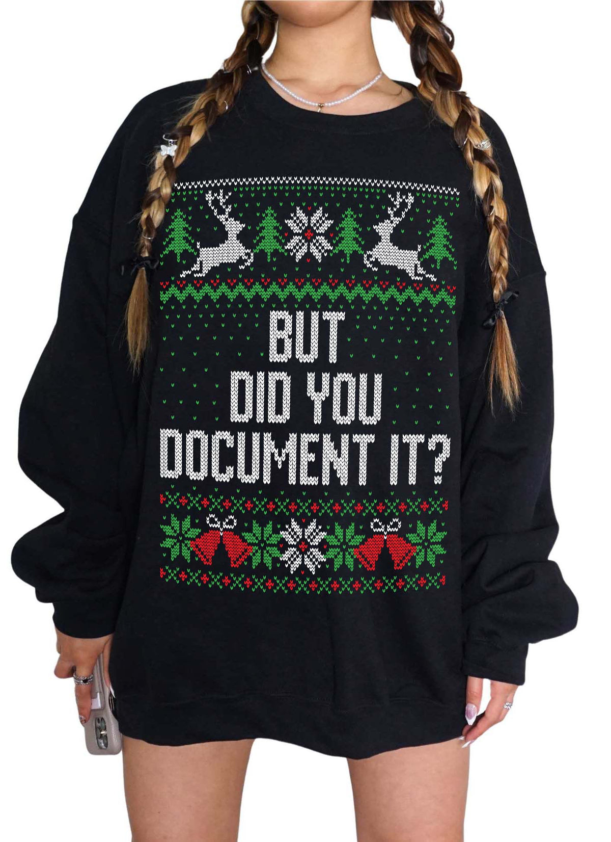 A person wearing a black oversized Christmas sweater with a festive green, red, and white knit pattern featuring reindeer, snowflakes, and the text 'BUT DID YOU DOCUMENT IT?' on the front.