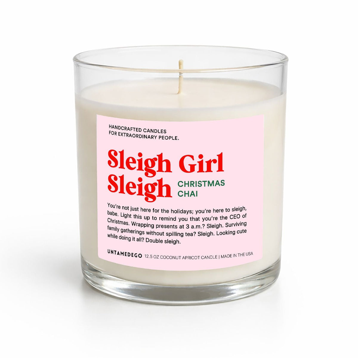 A handcrafted jar candle with a clear glass container, white wax, and a pink label reading 'Sleigh Girl Sleigh Christmas Chai' by UnAmerica, shown on a white background.