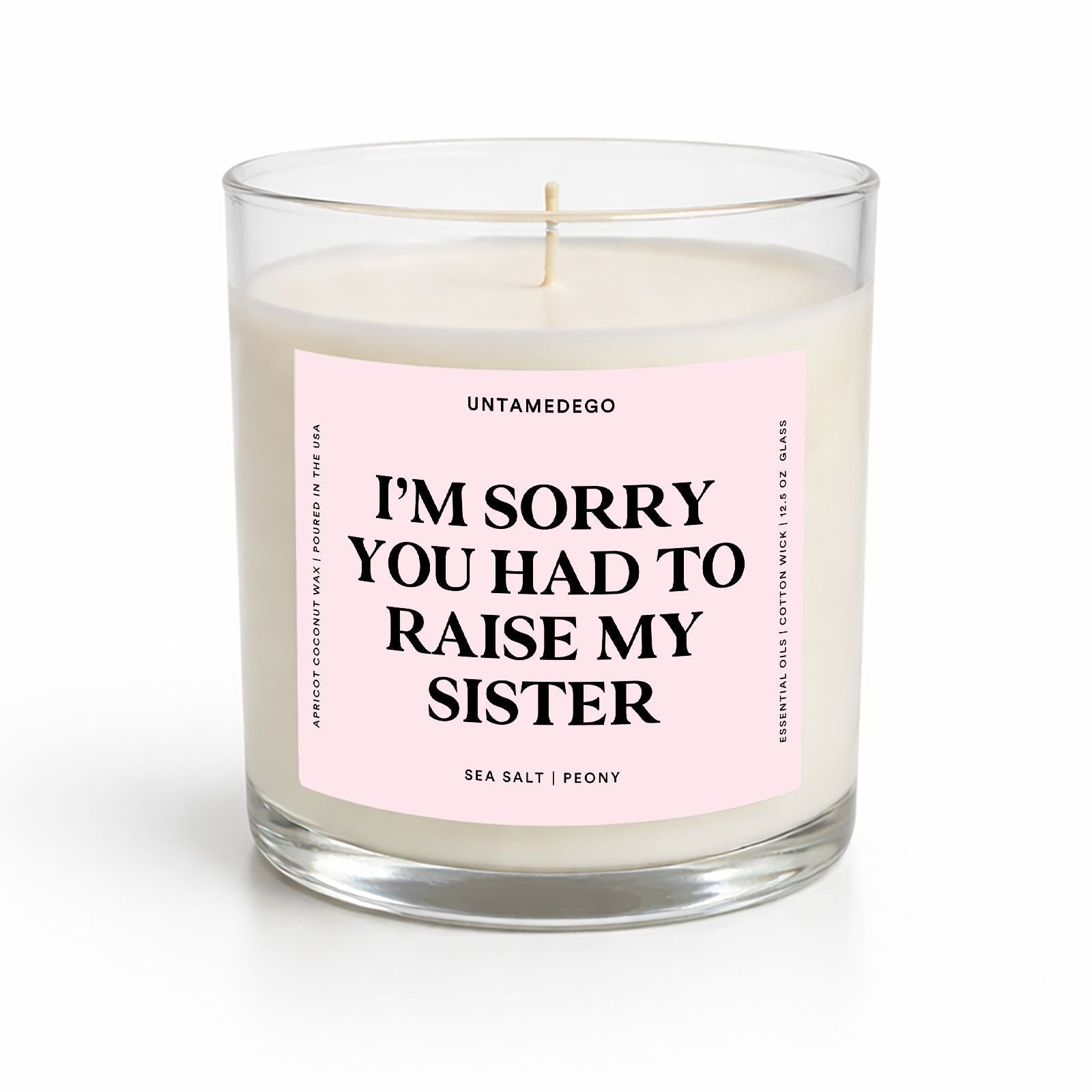 Candle with a pink label reading 'I'm sorry you had to raise my sister' on a white background