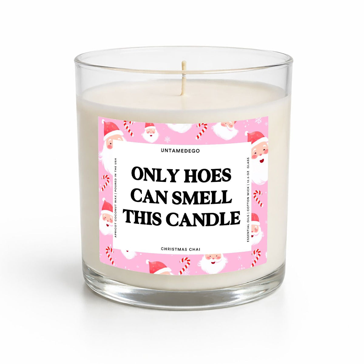 A clear glass jar candle with white wax and a humorous pink Christmas label that reads 'ONLY HOES CAN SMELL THIS CANDLE' with Santa illustrations around the border. The brand 'UNTAMEDSO' is visible at the top of the label.