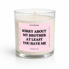 A single-wick soy candle in a clear glass jar with a pale pink label that reads 'SORRY ABOUT MY BROTHER AT LEAST YOU HAVE ME' in bold black text. The brand name 'UNTAMEDEGO' is visible at the top of the label.
