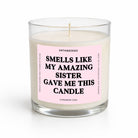 A glass jar candle with white wax and a pink label that reads 'SMELLS LIKE MY AMAZING Sister GAVE ME THIS CANDLE' by Untamedgo, shown on a white background.