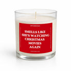 A glass jar candle with white wax and a red label that reads 'SMELLS LIKE SHE'S WATCHING CHRISTMAS MOVIES AGAIN' by Untamedeo, shown on a clean white background.