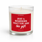 A white soy candle in a clear glass jar with a red square label that reads, 'JUST A REMINDER THAT YOU ARE the gift' in white text. The brand name 'UNTAMEDEGO' is visible at the top of the label.