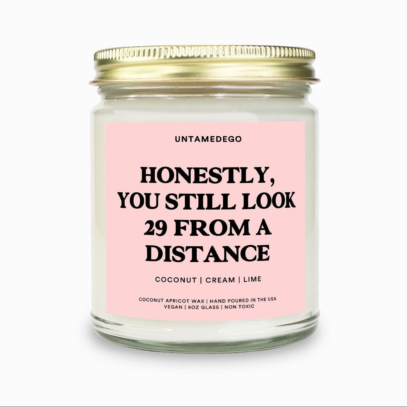 Candle with pink label and gold lid on a white background