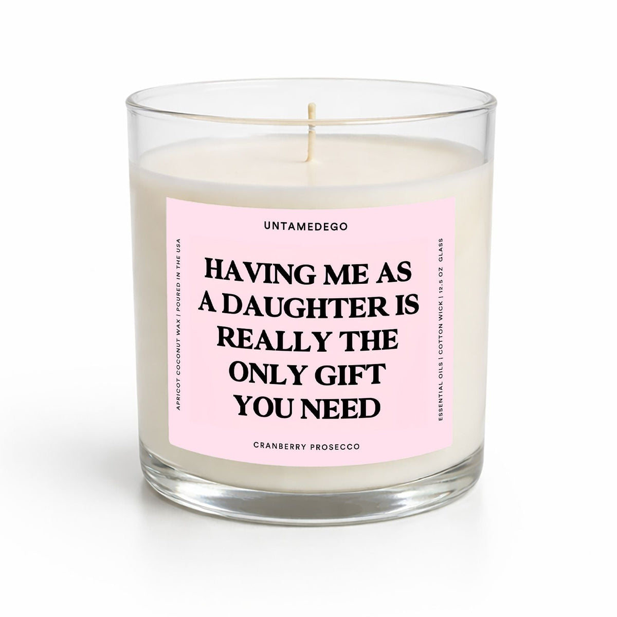 A single-wick soy candle in a clear glass jar with a pale pink label that reads, 'HAVING ME AS A DAUGHTER IS REALLY THE ONLY GIFT YOU NEED' by Untamedgo. The candle is photographed on a clean white background.