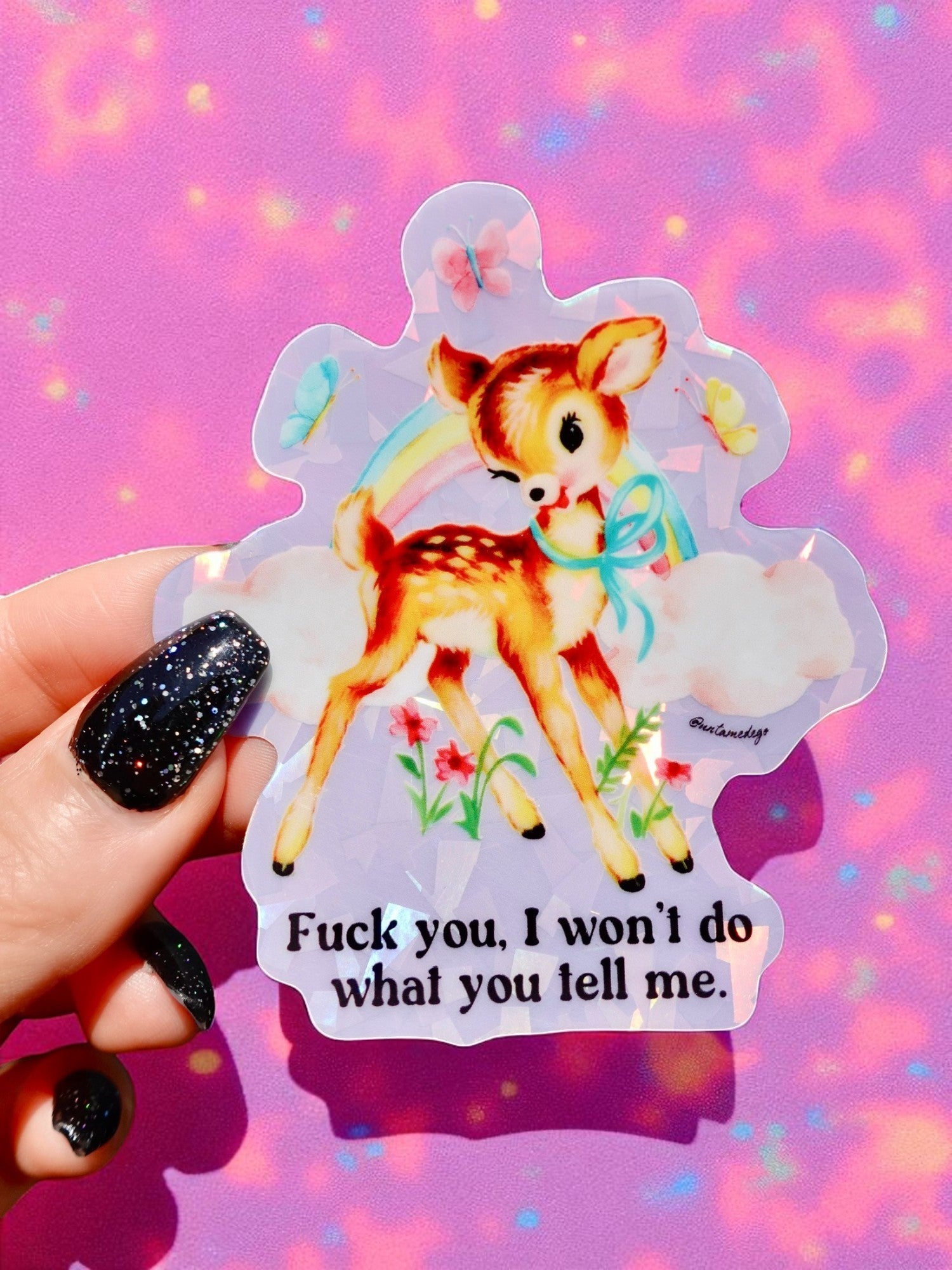 Sticker with a deer illustration and text held against a colorful, blurred background
