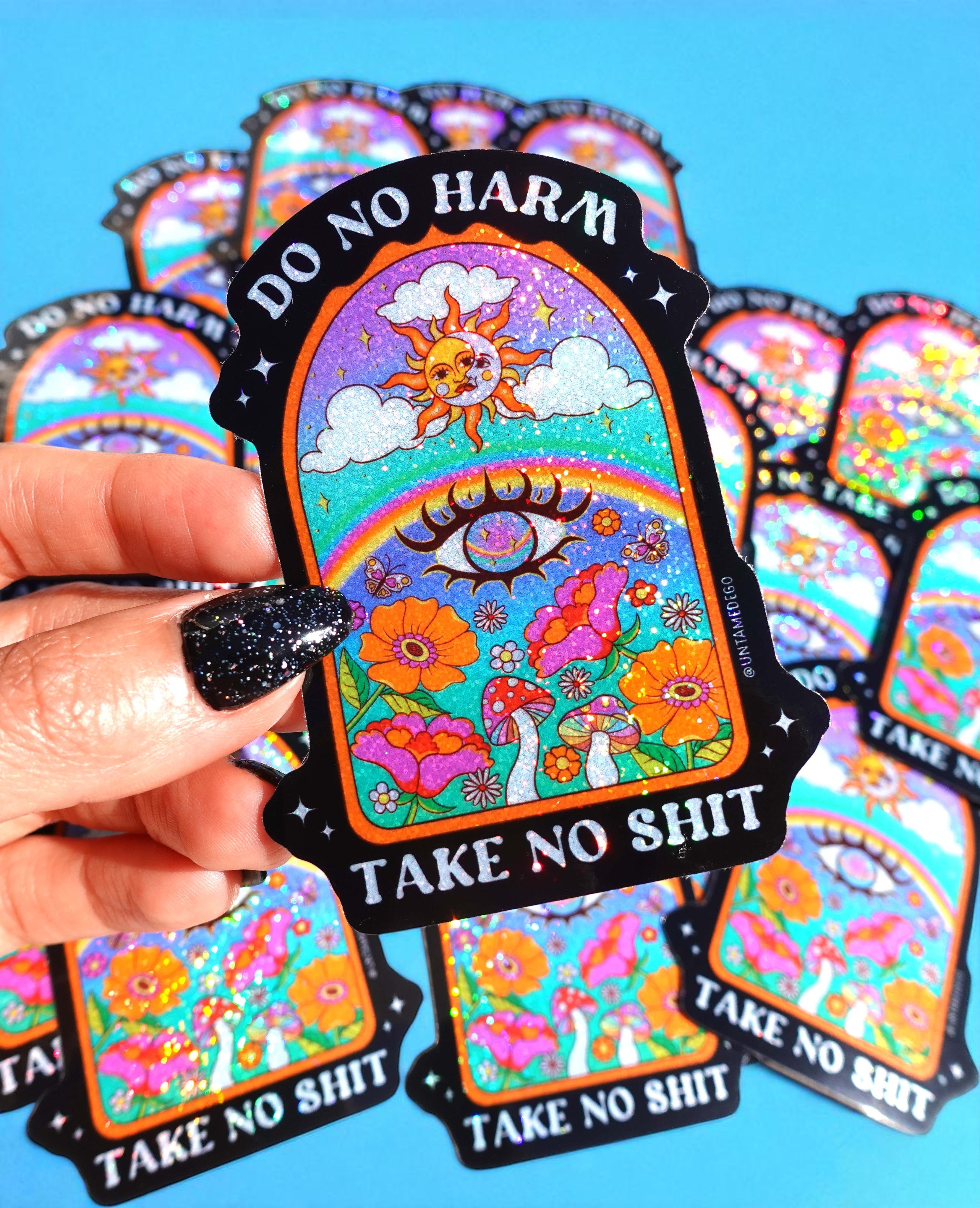 Colorful stickers with 'Do No Harm, Take No Shit' text held by a hand against a blue background.