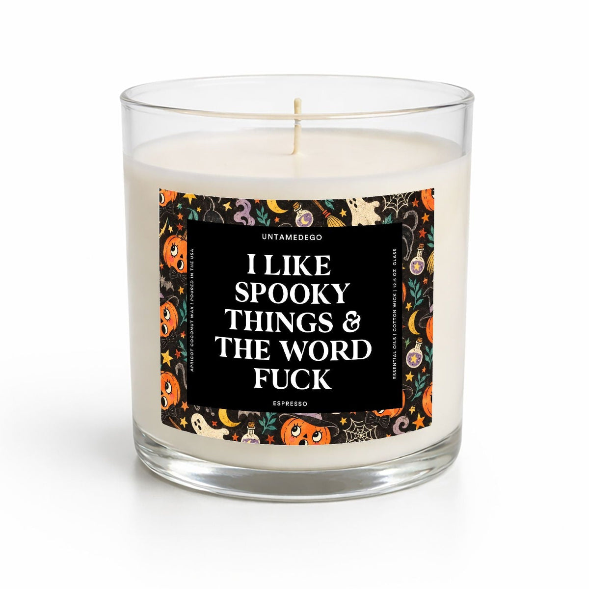 A clear glass jar candle with white wax and a single wick, featuring a Halloween-themed label with the text 'I LIKE SPOOKY THINGS & THE WORD FUCK' on a white background.